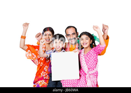 Felice indiano famiglia rurale- genitori con 2 bambini seduti insieme e che mostra una lavagna bianca allegro godendo su sfondo bianco Foto Stock