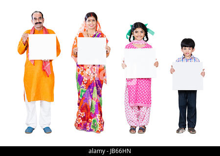 Indian famiglia rurale- i genitori e 2 bambini Code permanente insieme tenendo una lavagna bianca Foto Stock