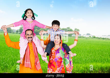 Felice agricoltore rurale famiglia- i genitori tenendo i bambini sulle spalle nel campo Foto Stock