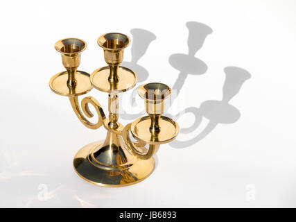 Candelabro d'oro su sfondo bianco con ombre di close-up Foto Stock