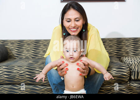 2 persone donna adulta a casa baby inizio boy aiutando holding sorridente in piedi Foto Stock