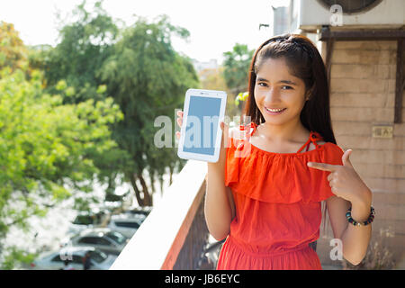 1 persona solo al balcone di casa digitale compressa dito di puntamento ragazza sorride mostrando adolescente Foto Stock