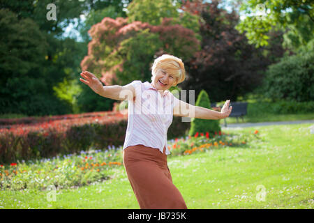 L'allegria. Felice giocosa donna matura con le braccia tese a ridere al di fuori Foto Stock