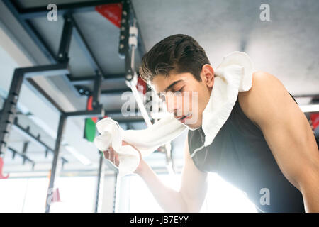 Montare giovane uomo ispanico in palestra tergi sudore il suo volto Foto Stock