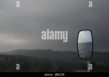 La riflessione in ala specchio della barca sul Loch Lomond in Scozia su moody, tempestoso giorno in autunno Foto Stock