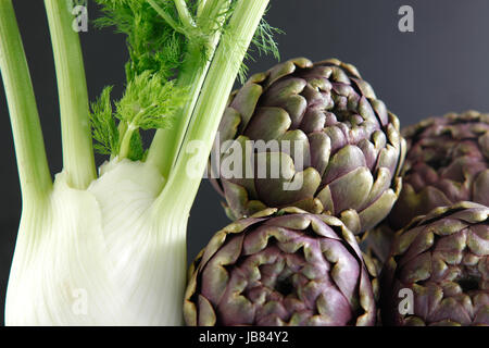 Il finocchio e quattro i carciofi su sfondo scuro Foto Stock