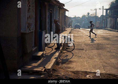 Un vecchio uomo cubani che arrivano a casa sulla sua bicicletta come il sole tramonta in Trinidad, Cuba Foto Stock