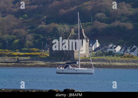 Barca a Vela passa le rovine del castello di Lochranza su una soleggiata giornata di primavera. Lochranza, Arran, Scozia. Aprile 2017. Foto Stock