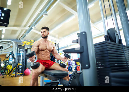 Culturista con manubri in palestra Foto Stock