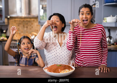 Felice multi-generazione famiglia mangiare spaghetti in cucina a casa Foto Stock