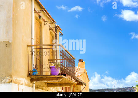 Vecchio balcone di legno con il ferro battuto recinzione. Muro di pietra con porte di legno intagliato. Resort classic architettura greca nella città portuale di Rethimno, Creta, greco Foto Stock