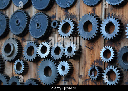 Un einer Wand sortierte, alte Zahnräder Foto Stock