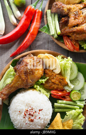 Popolare indonesiano cibo locale nasi ayam penyet, indonesiano fritto di pollo riso. Caldo fresco con vapore di fumo. Foto Stock