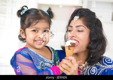 Mangiare gelato. Felice Asian India la Condivisione in famiglia di gelati a casa. Bellissima bambina indiana madre di alimentazione. Foto Stock