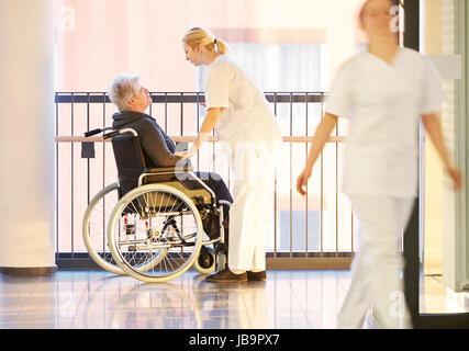 Rollstuhl und Patientin im Krankenhaus mit Krankenschwestern Foto Stock