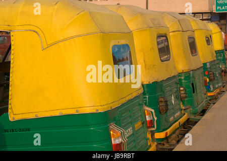 Fila di giallo risciò motorizzati al di fuori alla stazione ferroviaria di Nuova Delhi a Delhi, India. Foto Stock