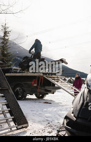 Caricamento uomo motoslitta su van durante il periodo invernale Foto Stock