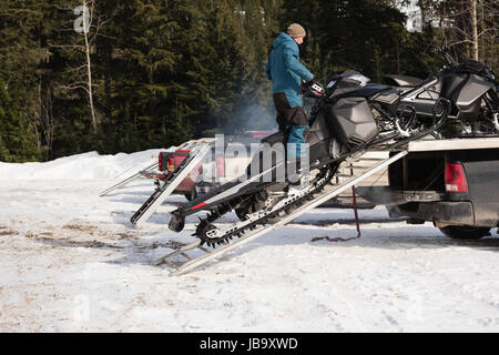 Caricamento uomo motoslitta su van durante il periodo invernale Foto Stock