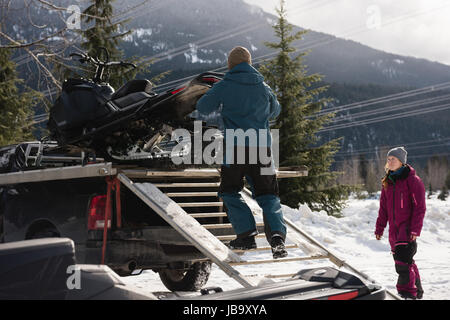 Caricamento uomo motoslitta su van durante il periodo invernale Foto Stock