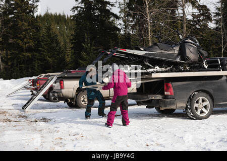 Accoppiare il carico motoslitta su van durante il periodo invernale Foto Stock