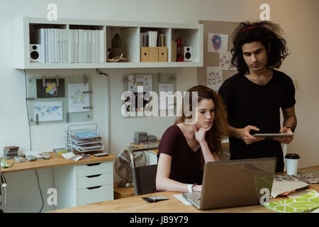 Colleghi di lavoro lavorando insieme alla scrivania in ufficio Foto Stock