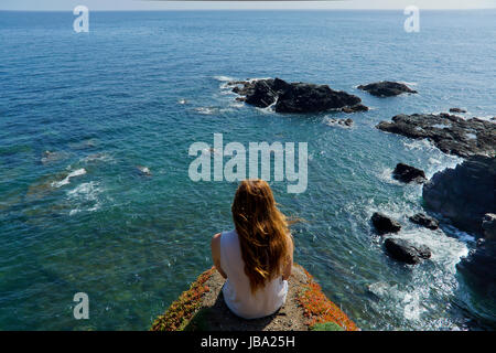 Una giovane donna si affaccia sul mare dal punto di lucertole in Cornwall, Regno Unito Foto Stock