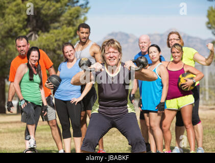 Grinning donna matura bollitore di sollevamento pesi a campana con il gruppo Foto Stock