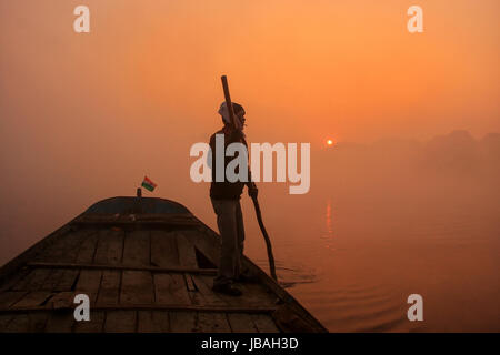 Uomo locale spostando barca sul fiume Yamuna con un palo di sunrise, Agra, Uttar Pradesh, India. Agra è una delle più popolose città in Uttar Pradesh Foto Stock