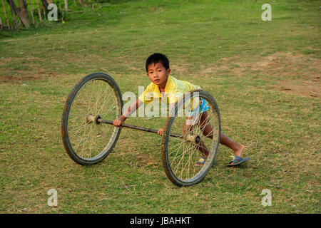 Capretto locale a giocare con le ruote in Vang Vieng, Laos. Vang Vieng è un complesso turistico-oriented cittadina in provincia di Vientiane. Foto Stock