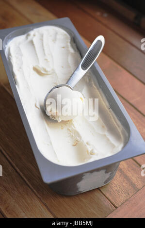 Organico in casa di gelato alla vaniglia scoop, raccolto fuori di un contenitore Foto Stock