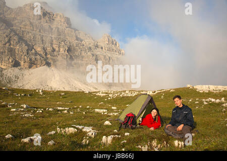 Junge Leute zelten beim Wandern in den Bergen mit Textfreiraum Foto Stock