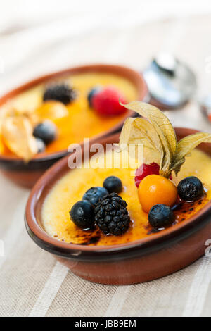 Dolce creme brulee dessert guarnita con frutti di bosco freschi Foto Stock