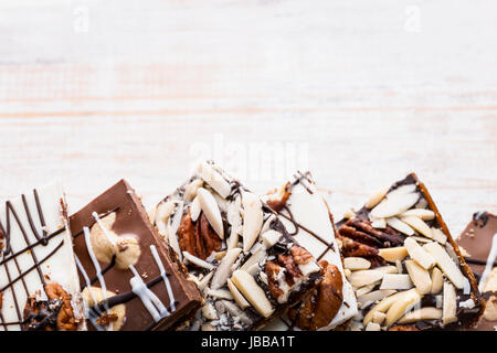 Un assortimento di cioccolato di corteccia di caramello pezzi disposti su sfondo di legno dal di sopra con lo spazio di copia Foto Stock