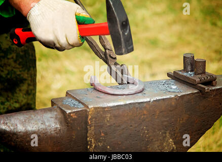 In una piccola fucina fucina di un ferro di cavallo a caldo. Il lavoro manuale. Foto Stock