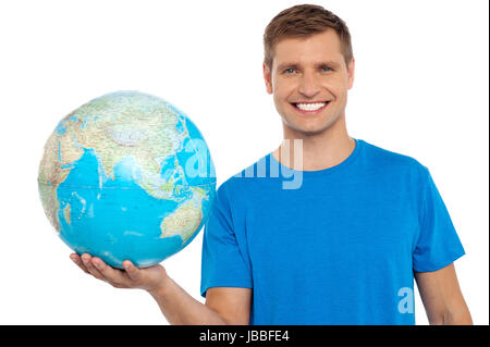 Giovane uomo allegro tenendo un globo in sua mano isolate su sfondo bianco Foto Stock