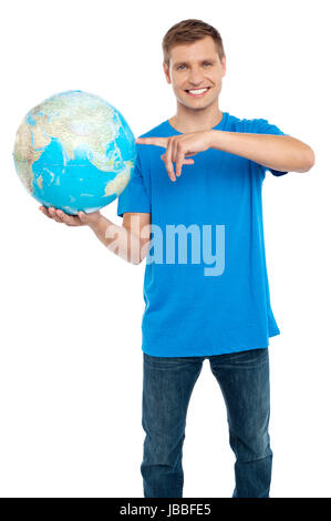 Smart guy puntando verso il mondo. Vestito di casuals. Isolato su bianco Foto Stock