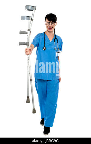 Giovani energica medico ortopedico camminando verso la telecamera con le stampelle in mano. Foto Stock