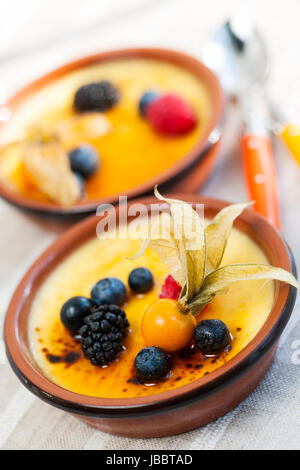 Dolce creme brulee dessert guarnita con frutti di bosco freschi Foto Stock