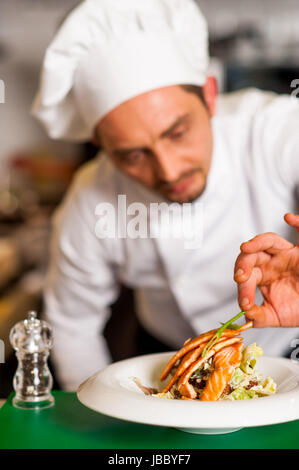 Chef di aggiungere il tocco finale al delizioso salmone al forno Foto Stock