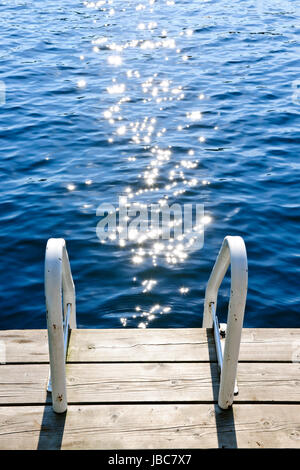 Dock e la scala sul tranquillo lago d'estate con acqua frizzante in Ontario Canada Foto Stock