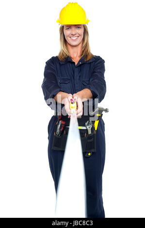 Bella donna ingegnere in uniforme di stiro del nastro di misurazione. Isolato su bianco. Foto Stock