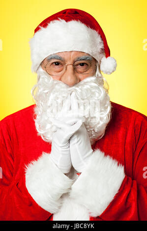 Riflessivo Santa Claus indossando occhiali,su sfondo giallo Foto Stock