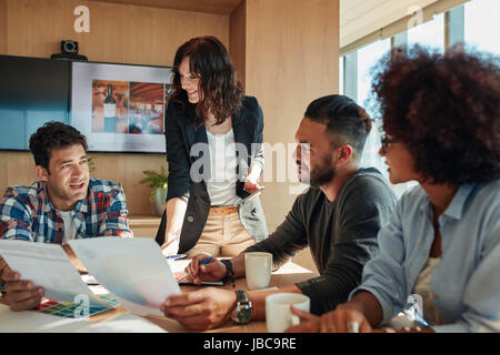 Un gruppo di giovani persone per discutere il nuovo schema di colori per progetto. Il brainstorming Team in sala riunioni con tavolozze di colori. Foto Stock