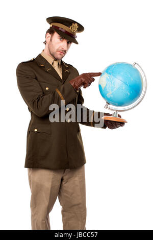 Giovane ufficiale militare azienda mappa del globo e indicante Foto Stock