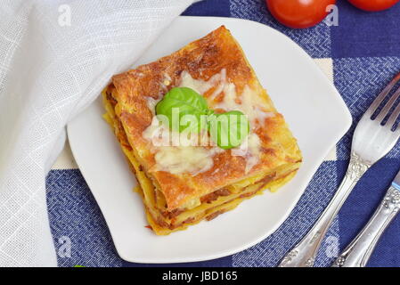 Strato di lasagne fatte in casa con la carne macinata, pomodoro, formaggio su una piastra bianca. Mangiare sano concetto. Foto Stock