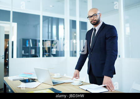 Imprenditore gravi in piedi dal suo posto di lavoro Foto Stock