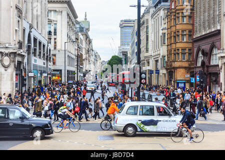 Un gruppo di ciclisti, taxi, auto e pedoni cross Oxford Street a Oxford Circus nel traffico, London, Regno Unito Foto Stock