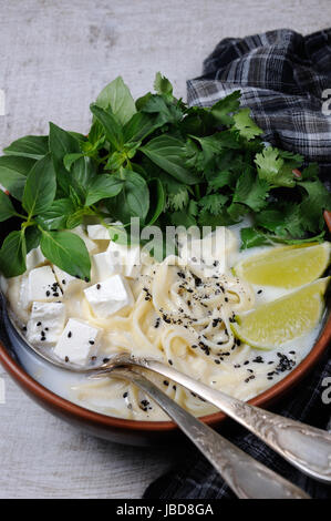 Una zuppa di riso con le tagliatelle e tofu insaporito con limone erba (basilico), il coriandolo, sesamo. Foto Stock