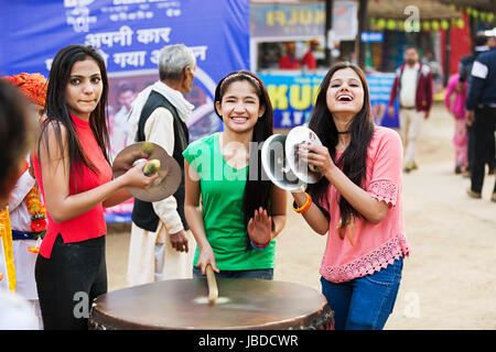 3 adolescente ragazze amici Drumming Drum divertimento godere Surajkund Mela Foto Stock