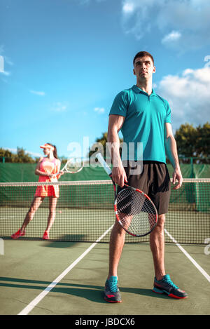 L uomo e la donna gioca a tennis in aria aperta. Stagione estiva gioco di sport. Uno stile di vita attivo Foto Stock